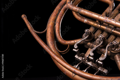 Vintage bronze pipes, valve, key mechanical elements french horn, black background. Good pattern, prompt music instrument.
