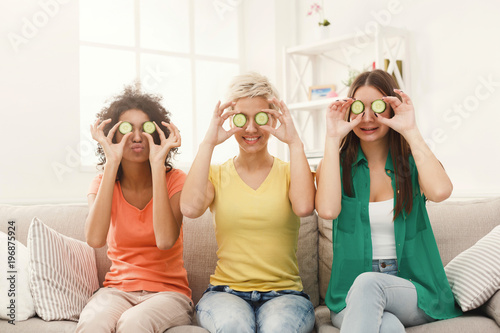 Three beautiful girls covering eyes with cucumber pieces photo