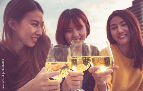 Happy group of asia girl friends enjoy laughing and cheerful toast sparkling wine glass at rooftop party,Holiday celebration festive,teeage lifestyle,freedom and fun.