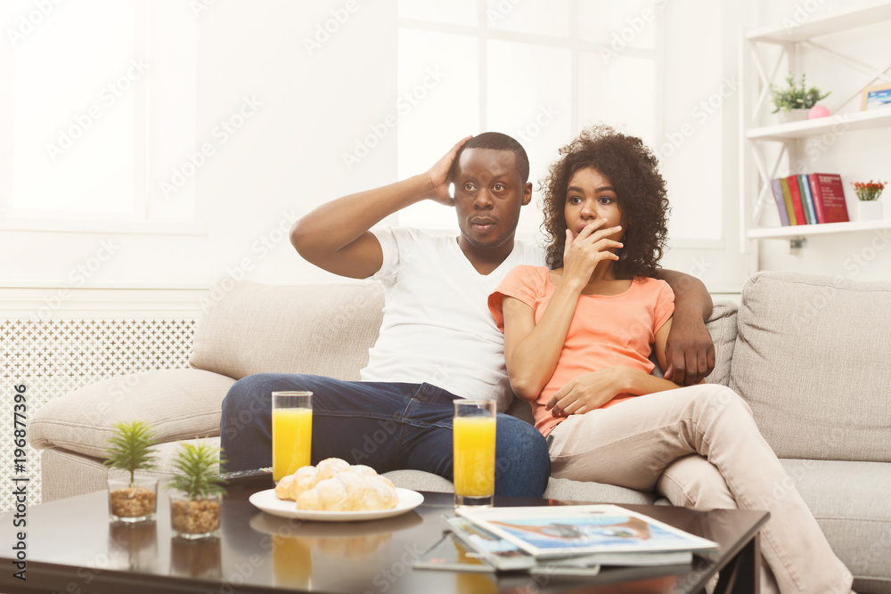Scared african-american couple watching TV at home Scared african-american couple watching TV at home