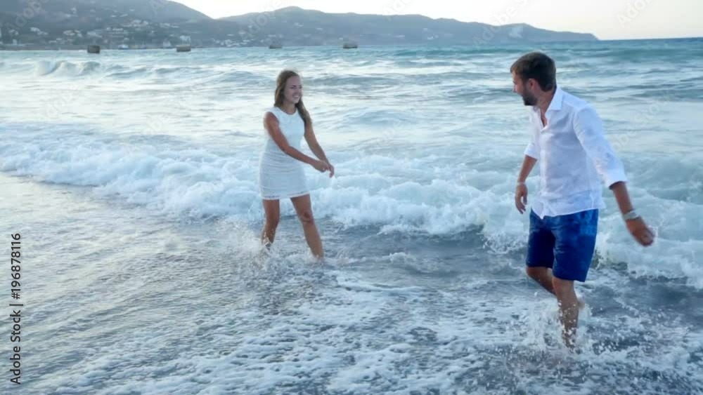 A guy and a girl are having fun on the beach. Bride and groom by the sea on their wedding day. Wedding photosession. Greece A guy and a girl are having fun on the beach. Bride and groom by the sea on their wedding day. Wedding photosession. Greece