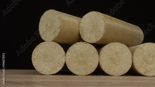 Wood sawdust briquettes straightened, black background. Alternative fuel, bio fuel. Slider shot