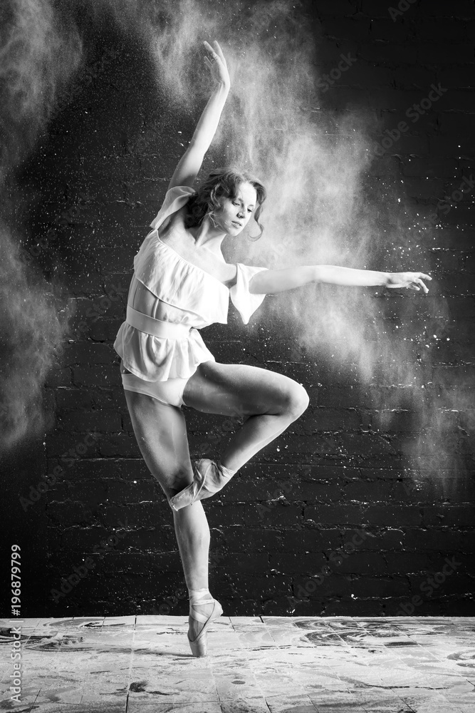 beautiful ballet dancer in white clothes dancing on Pointe in a cloud of dust