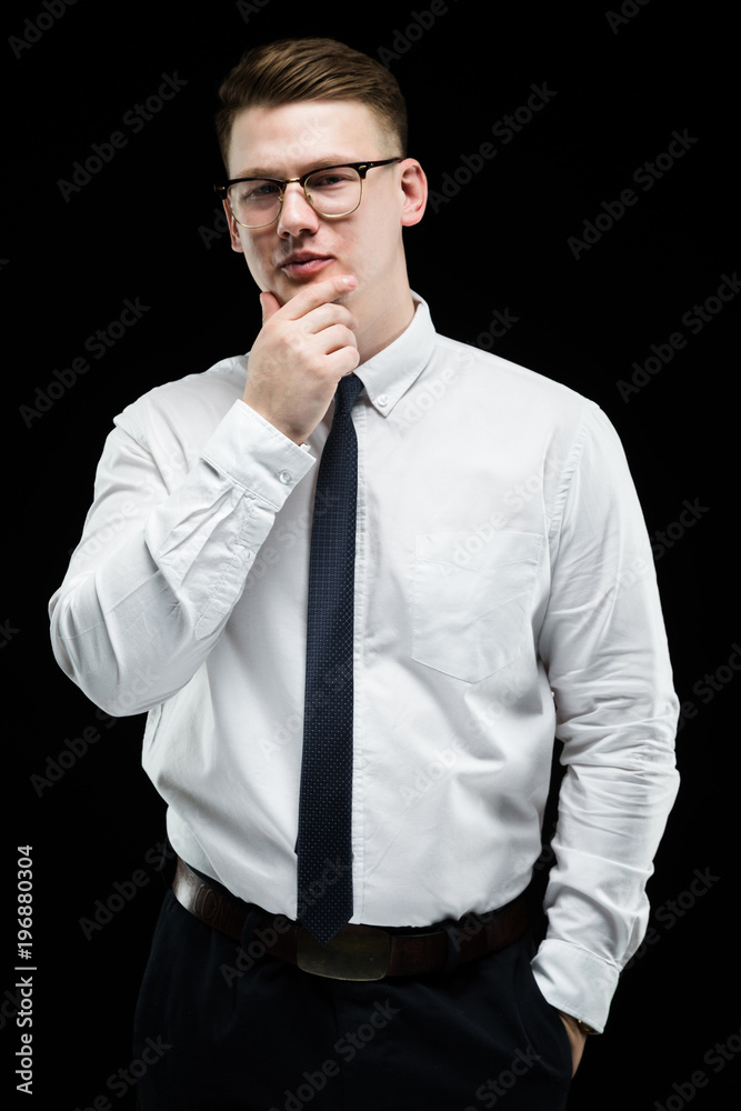 Portrait of confident handsome elegant responsible businessman with hand on his chin on black background Portrait of confident handsome elegant responsible businessman with hand on his chin on black background