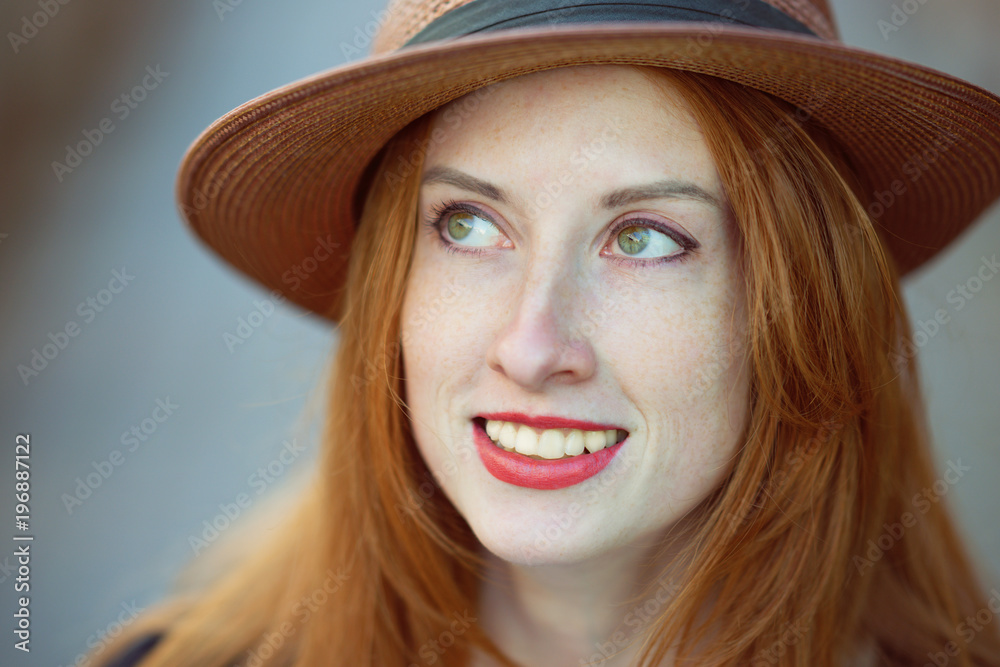 Portrait of a beautiful girl in a hat with long red hair 