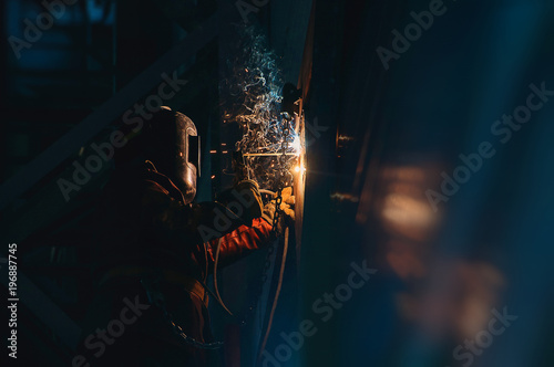 Man welder at work sparks wall metal welding