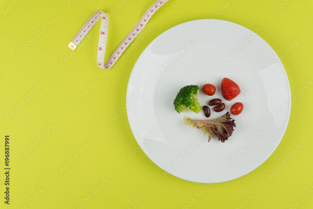 Diet concept : small amount of food on the white plate with a measuring tape.