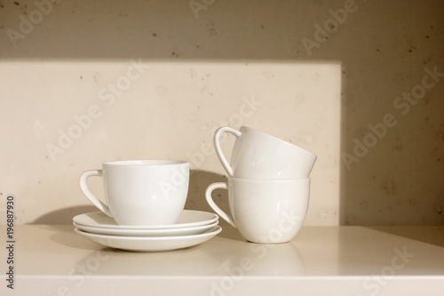 white ceramic cups and saucer on a shelf