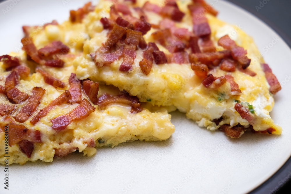 Plate full of fresh cooked omelette with bacon on dark background. Plate full of fresh cooked omelette with bacon on dark background.