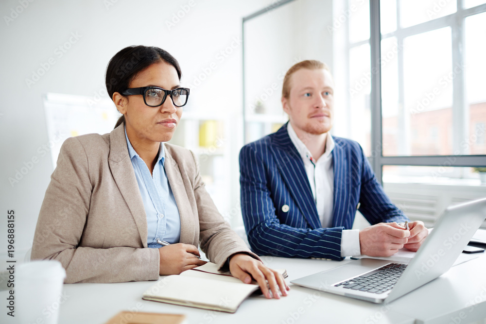 Portrait of two business peoplle sitting at meeting at office Portrait of two business peoplle sitting at meeting at office