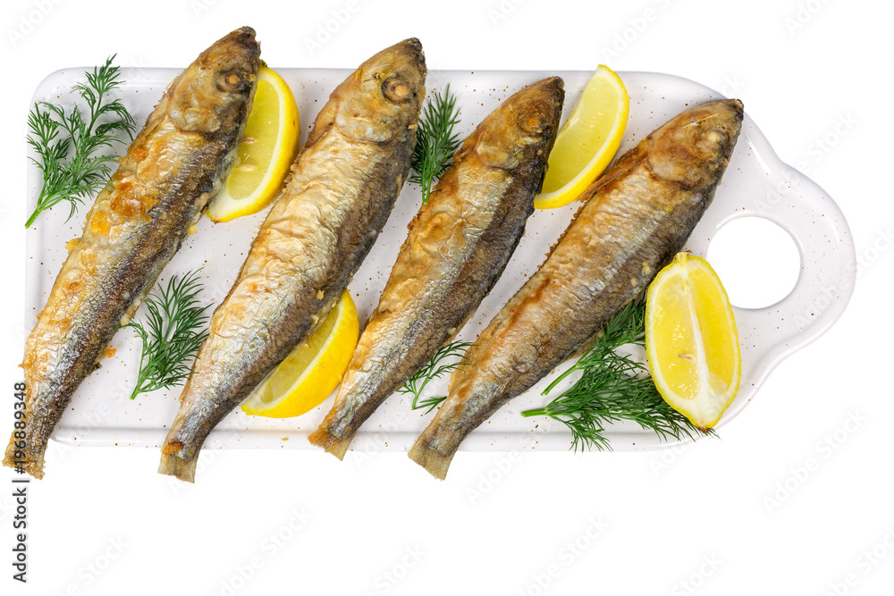 fried baltic herring with lemon on cutting board isolated on white background fried baltic herring with lemon on cutting board isolated on white background
