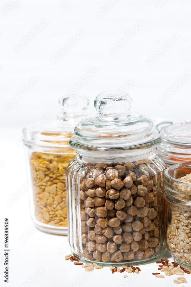 assortment of cereals and legumes in glass jars on white background, vertical assortment of cereals and legumes in glass jars on white background, vertical