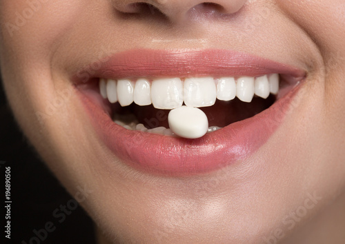 Joyful girl is showing white healthy teeth with chewing gum into mouth. Fresh breath concept. Close up