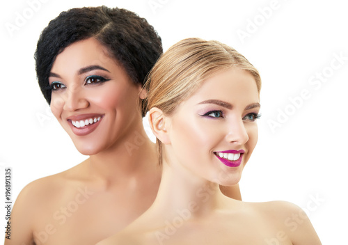 Caucasian blond girl and beautiful young woman posing in studio over white background. Fashion, beauty, glam, youth, makeup. Two beautiful different cheerful female models with perfect smiles.