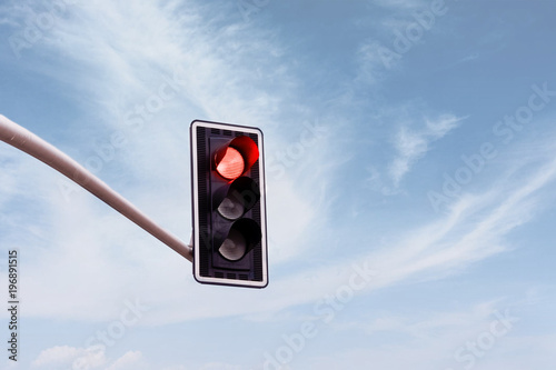 Red traffic light on a horizontal white metal beam, isolated on sky background photo