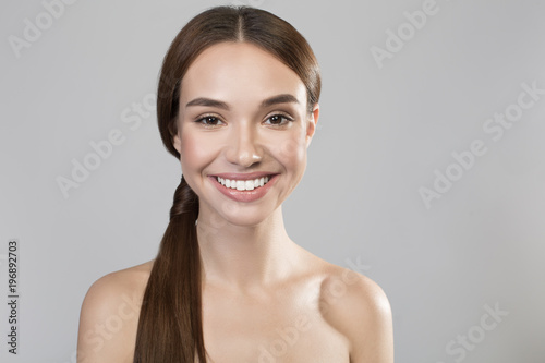 Happy glance. Portrait of cheerful naked positive girl is looking at camera with joy. She is demonstrating her perfect and fresh skin. Isolated background