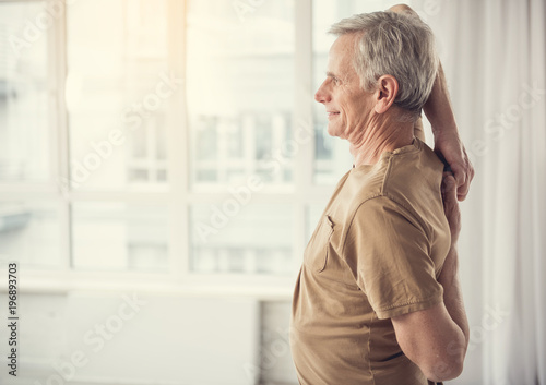 Side view profile of cheerful mature man with hands hooked behind his back. Copy space in left side photo