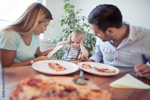 Family with pizza in kitchen.