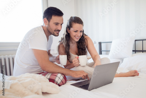 Young couple with laptop in the bed