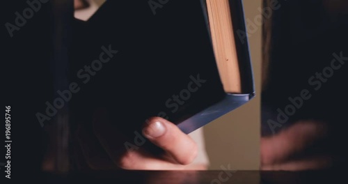 The man takes the book from the shelf and flips through it.