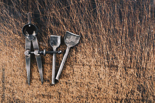 Leather craft tools on a wooden background. Leather craftmans work desk . Piece of hide and working handmade tools on a work table. photo