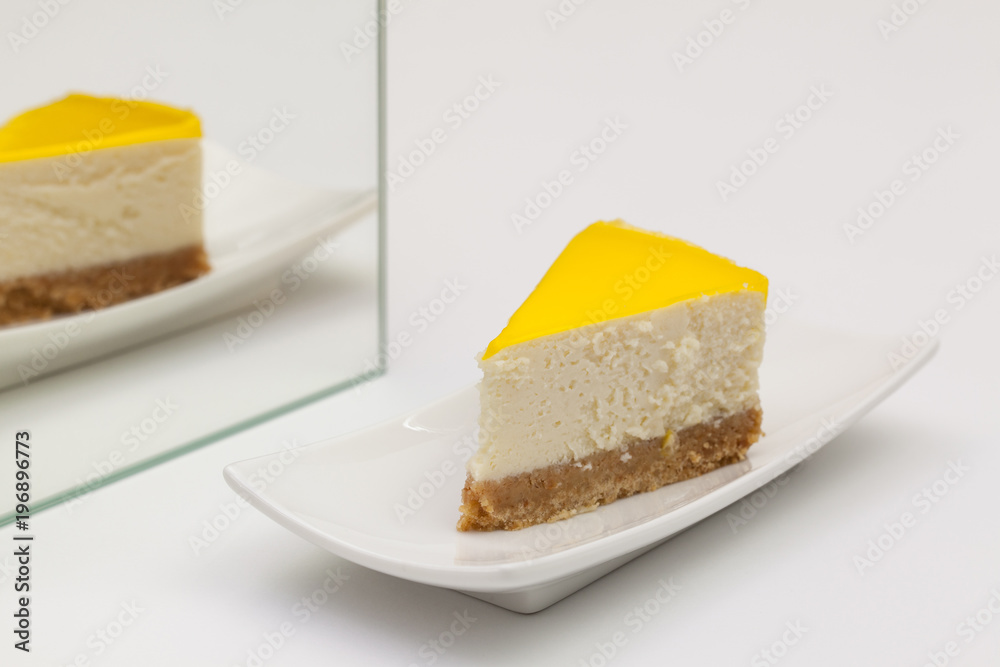 One piece of lemon cheesecake on a white plate. One piece of lemon cheesecake on a white plate.