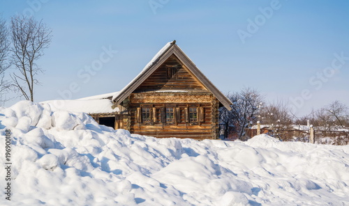 Village log cabin with carved shutters in the snow-covered village © allegro60