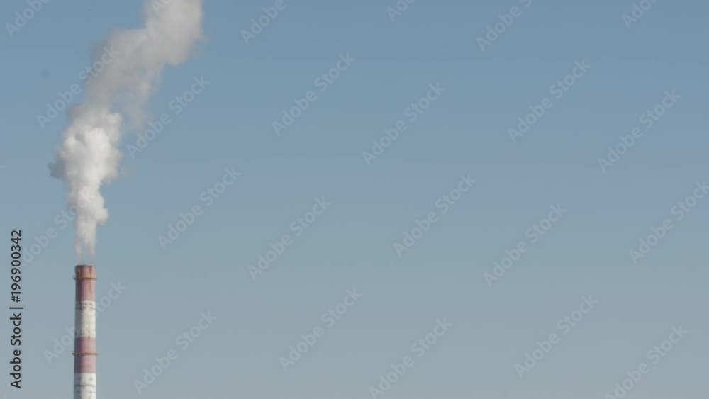 Medium shot of a smoke stack with a thick smoke plume. Beautiful blue sky.
