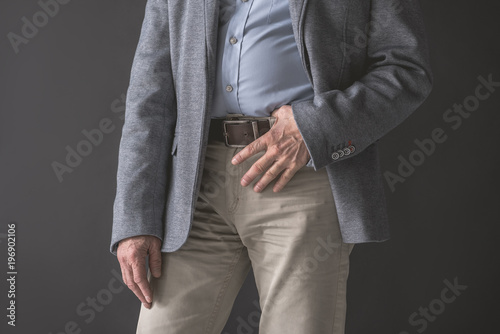 Close up old man hand keeping modern belt. He wearing modern suit. Fashion and business concept