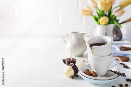 cup of coffee with yellow tulips isolated on white background.