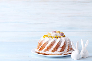 Tasty easter cake with ceramic rabbits on wooden table