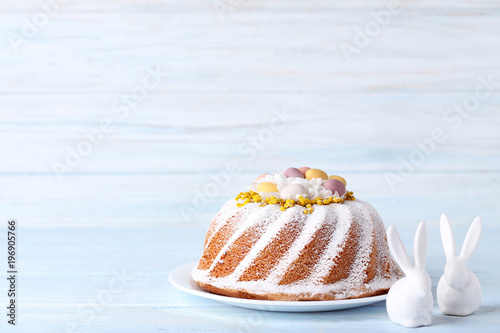 Tasty easter cake with ceramic rabbits on wooden table