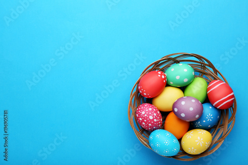 Colorful easter eggs in basket on blue background