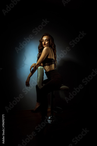 Gorgeous lady with curly hairstyle in dark studio