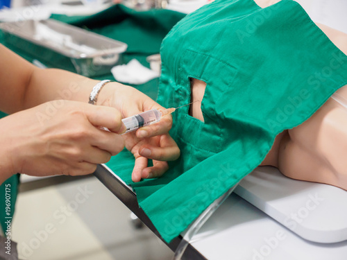 A physician practices a spinal block, a form of regional anesthesia, with a sterile drape on a pediatric training dummy. Healthcare and surgery concept.