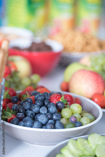 White bowl of fresh healthy fruit salad on wooden background