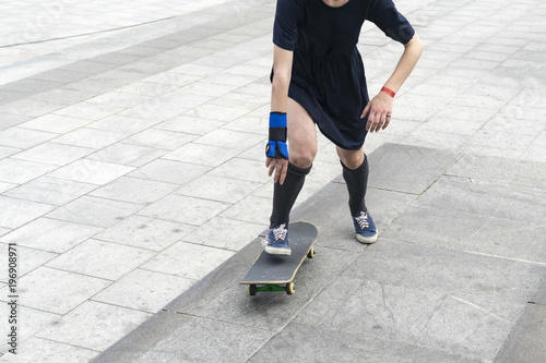 A girl or a woman in a skirt rides on a skateboard in the city, an extreme kind of sport, street sports