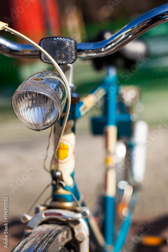 Close-up of the Headlight of a blue Retro Bicycle with black Saddle