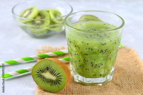 Sliced kiwi and smoothie slices in a glass on a gray table. Healthy food.