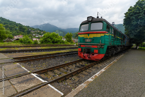 The old green locomotive stands at the railway station. In mountainous terrain