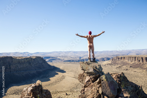Naked man standing on top of a mountain peak overlooking the valley. Taken in Frenchman Coulee, Vantage, Washington, America.