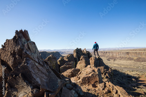 Obraz na plátne Naked man standing on top of a mountain peak overlooking the valley