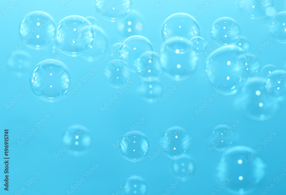 Abstract transparent soap bubbles float on a blue background.
