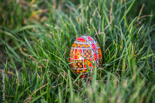 Traditionally painted Easter egg hidden in grass