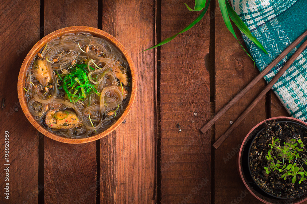 Japanese cuisine, soup with chashu pork, chives, sprouts, noodles and seaweed on the table under the sunlight. Wooden rustic background. Top view