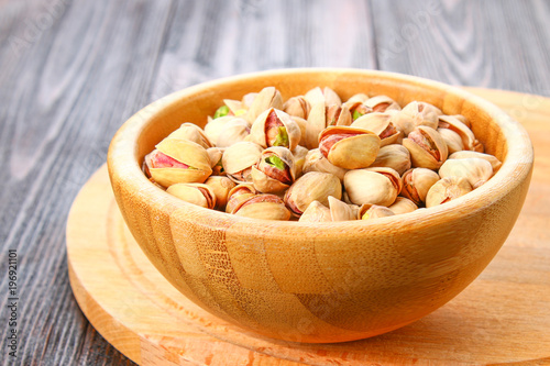 Dish full of pistachios with more pistachios on side. photo