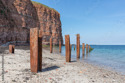 Photos Beach Helgoland island with red cliffs and rusty iron pillars of old putrefied j