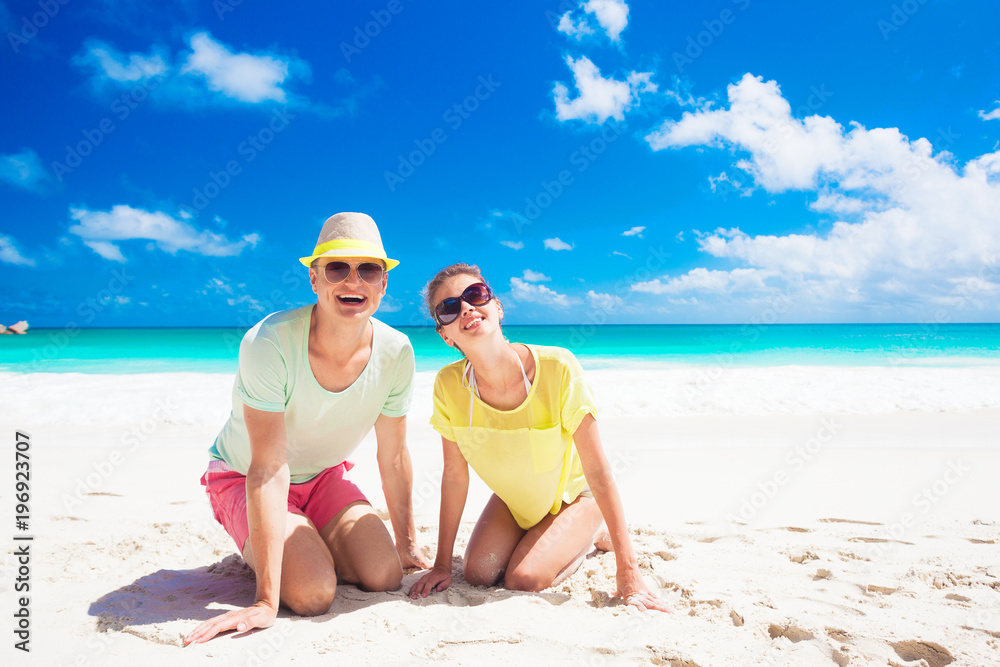 Couple in bright clothes on a tropical beach at Praslin, Seychelles.
