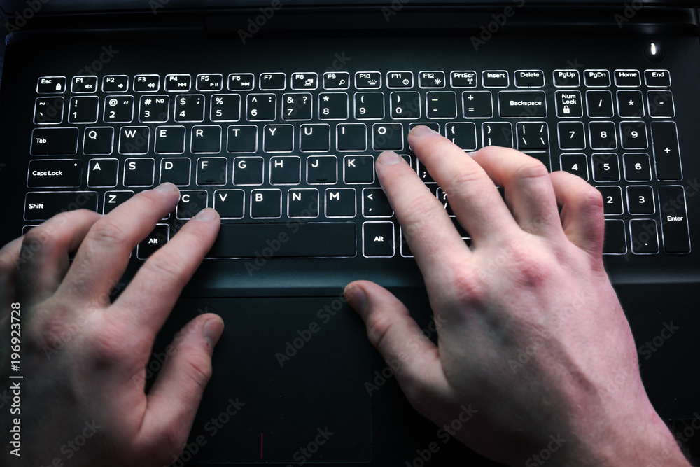 Male hands typing on a black laptop keyboard Male hands typing on a black laptop keyboard