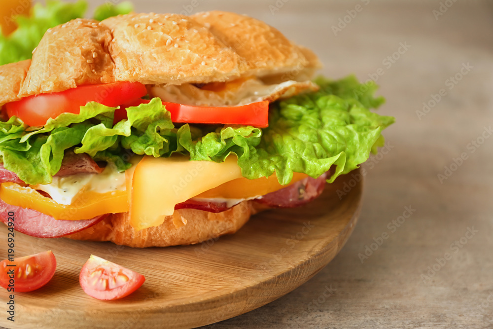 Wooden plate with tasty croissant sandwich, closeup Wooden plate with tasty croissant sandwich, closeup